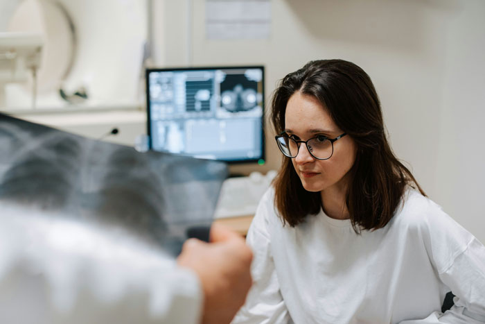 Young woman in glasses attentively listening in a medical setting, reflecting on refusing babysit stepsiblings concerns.