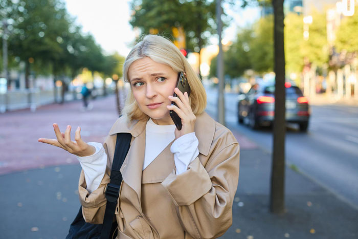 Young woman expressing frustration while talking on phone outdoors, illustrating refusing to look after brother’s children. Young woman expressing frustration while talking on phone outdoors, illustrating refusing to look after brother’s children.