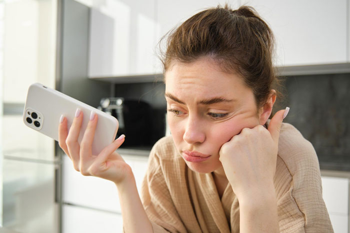 Woman showing refusal while looking at phone, reflecting refusing to watch autistic friend's show recommendation.