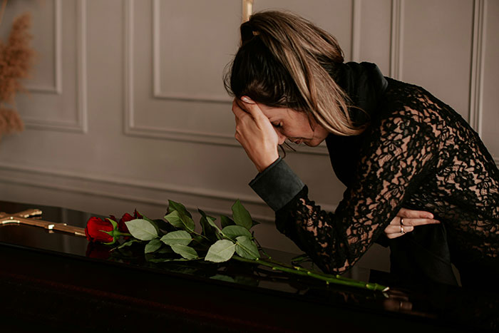 Woman in black lace dress holding her head, leaning on a piano with red roses, illustrating maddening and illogical reasons men got upset.
