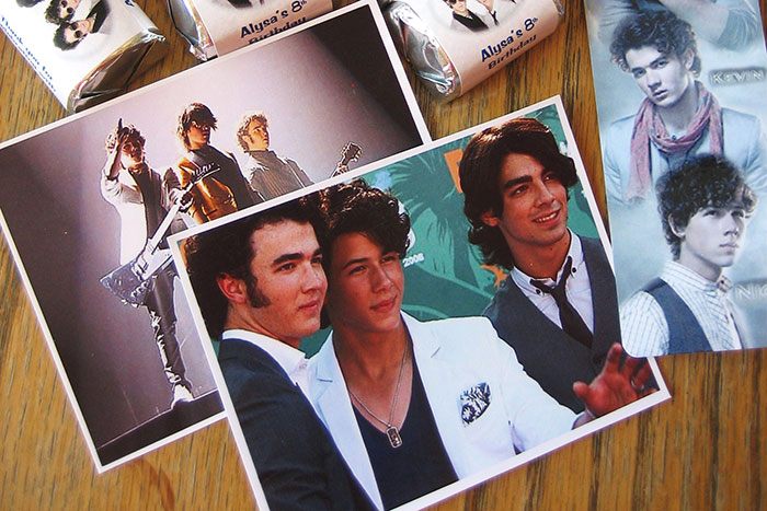 Photos of a popular boy band spread on a wooden surface, illustrating reasons men got upset at women.
