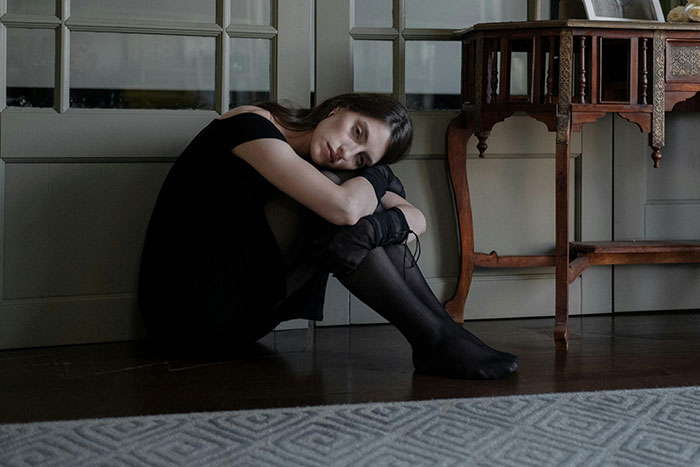 A woman sitting on the floor looking upset, illustrating maddening and illogical reasons men got upset at women.