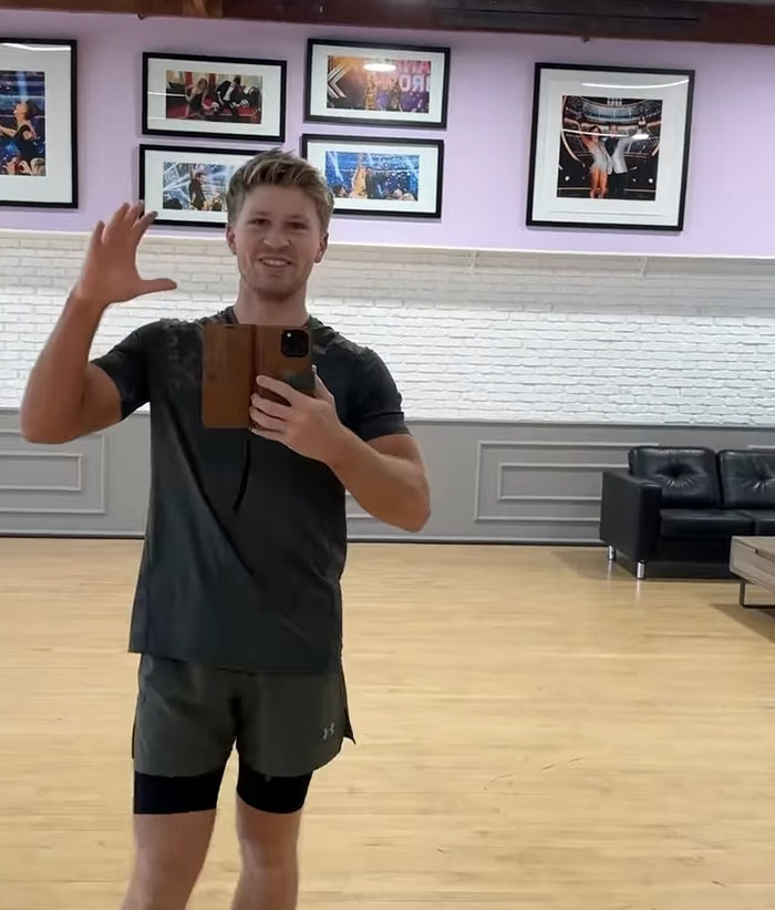 Man taking a selfie waving hand in a gym room with framed pictures on the wall leaving Australia news concept. Man taking a selfie waving hand in a gym room with framed pictures on the wall leaving Australia news concept.