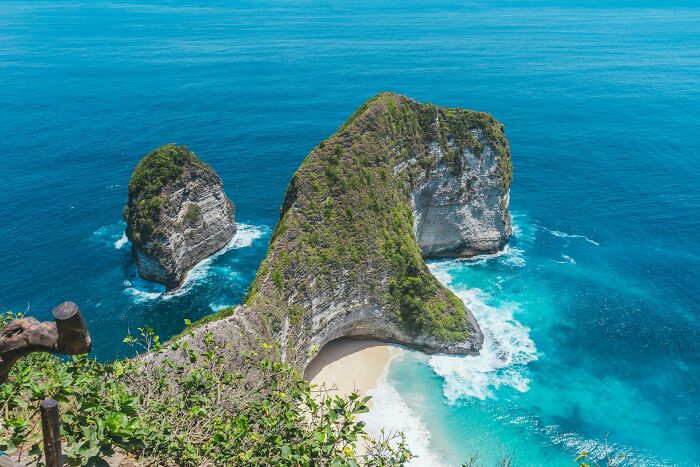 Aerial view of a tropical beach with cliffs and turquoise water at a popular travel destination.