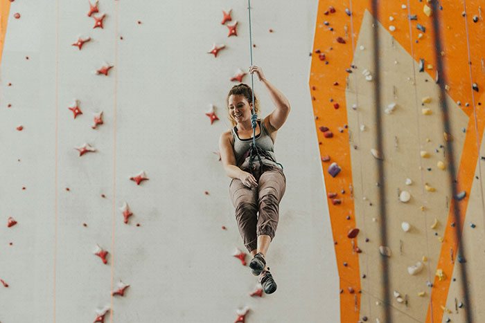 Woman suspended on climbing rope at indoor gym, reflecting on guy considering her his girlfriend after one date