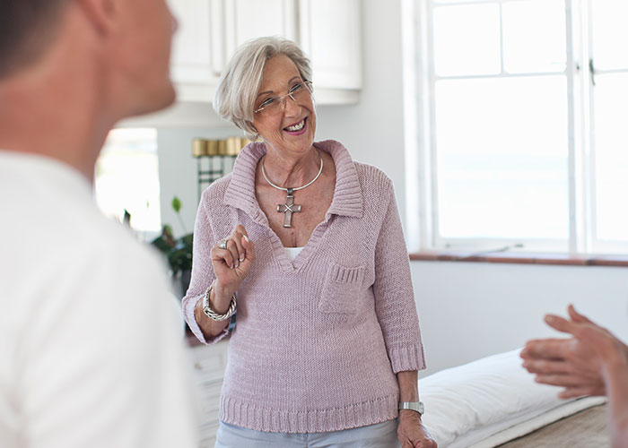 Older woman with glasses and cross necklace making a rude comment during a tense family conversation at home.