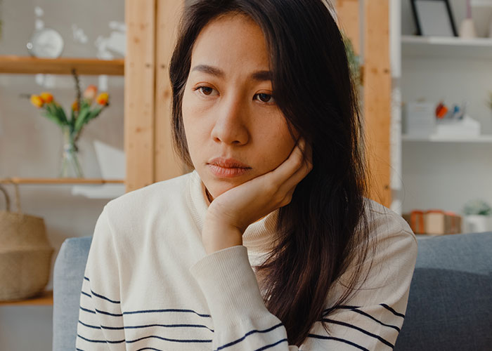 Woman looking upset and thoughtful at home, reflecting on years of rude comments from mother-in-law causing emotional strain.