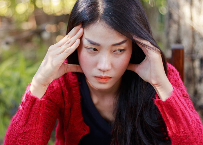 Young woman in a red sweater looking distressed, illustrating tension from years of rude comments by mother-in-law.