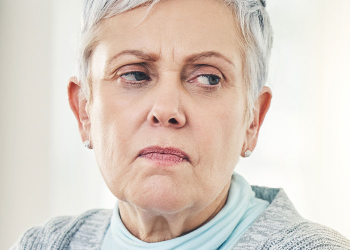 Older woman with a stern expression, symbolizing rude comments from mother-in-law causing emotional strain.