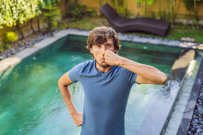 Man by a pool holding his nose in disgust, illustrating hilarious ways to ruin a first date quickly.