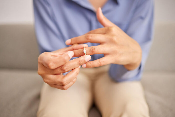 Person in a blue shirt sitting on a couch, removing a ring from their finger in a moment capturing first date emotions.
