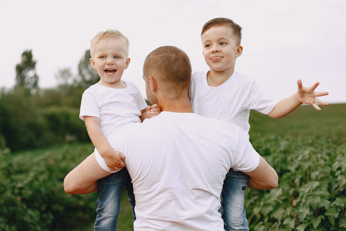 Man carrying two laughing children outdoors, illustrating hilarious ways to ruin a first date with unexpected family moments.