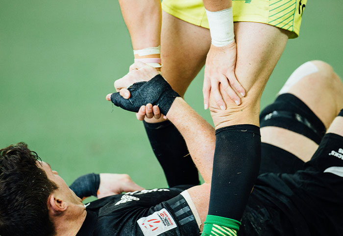 Rugby player receiving leg support during game, illustrating unintended consequences and how people can blow up someone's life.