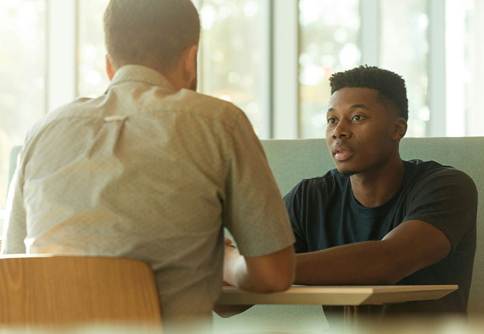 Two men having a serious conversation in a casual setting, illustrating how people can unintentionally blow up someone's life.