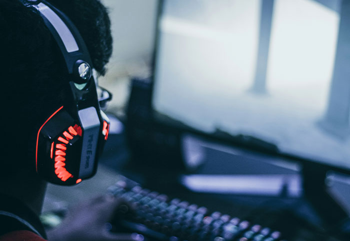 Person wearing headphones and using a keyboard, focused on a blurred computer screen, illustrating life blown up moments.
