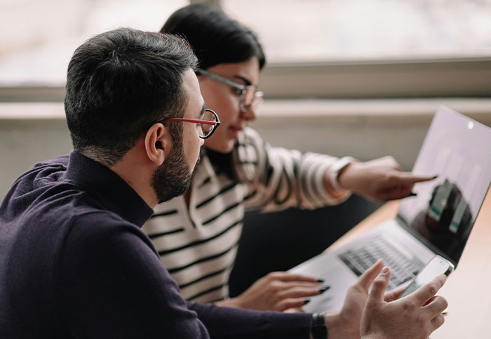 Two people discussing social media impact and how lives can be unintentionally affected while using a laptop and phone.
