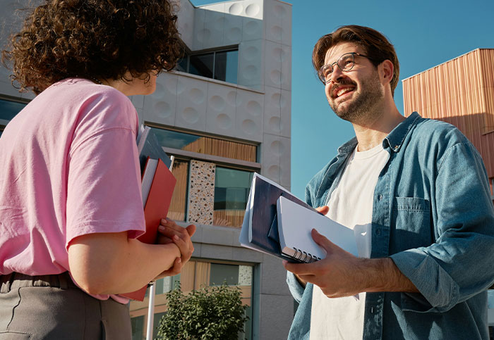 Two young adults discussing documents outdoors, illustrating the impact of how people unintentionally blew up someone's life.
