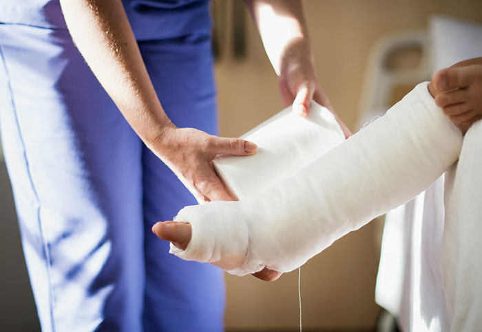 A healthcare professional wrapping a patient's arm in a bandage, illustrating unintended consequences of actions.