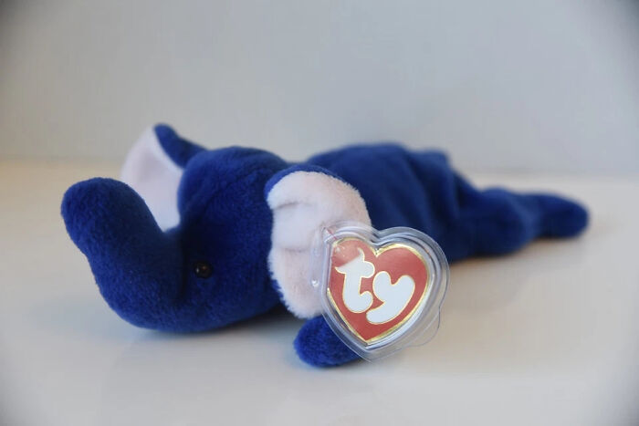 Blue vintage Beanie Baby elephant toy lying down with original ty heart tag, a collectible vintage toy worth fortune.