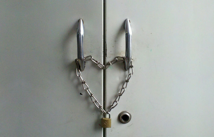 Metal cabinet doors secured with a chain and padlock symbolizing security concerns about creepy Airbnb host texts.
