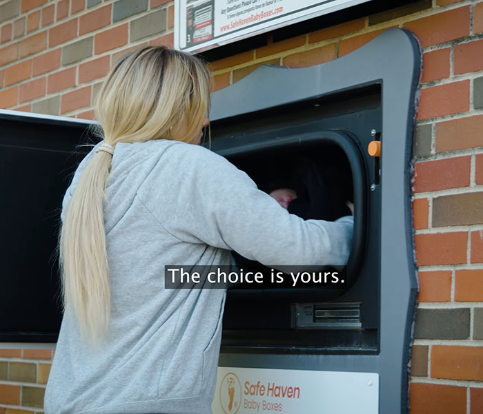 Woman placing a baby into a Safe Haven baby box outside a brick building, highlighting Kentucky cheerleader case details. Woman placing a baby into a Safe Haven baby box outside a brick building, highlighting Kentucky cheerleader case details.