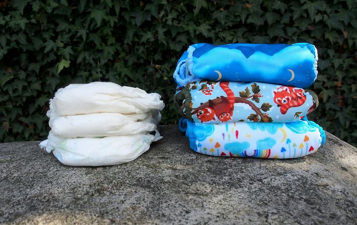 Stacked disposable and reusable diapers on a stone surface illustrating nasty things exes did that grossed out partners.
