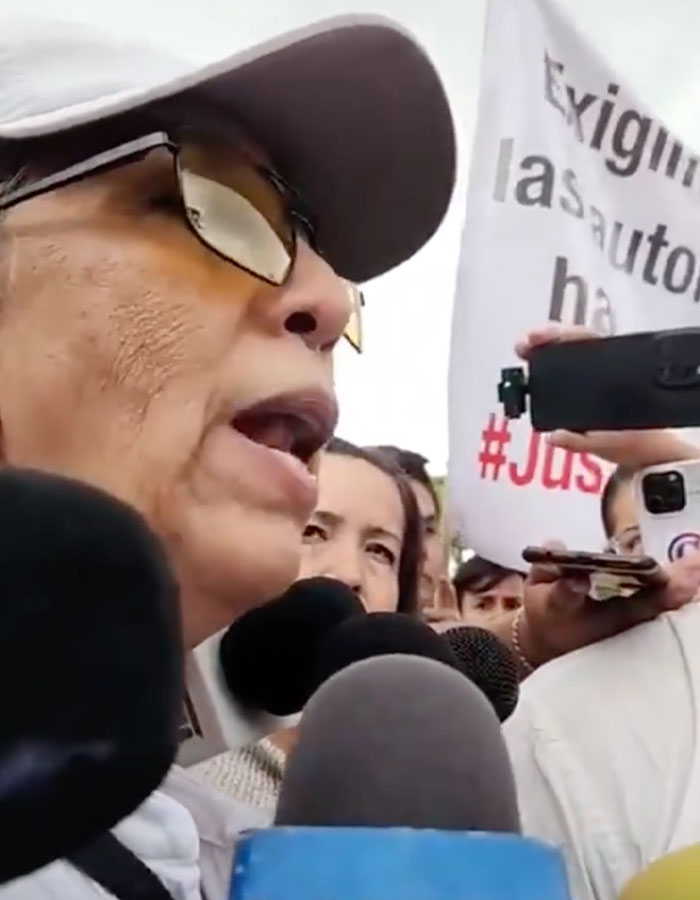 Woman speaking to reporters during a protest related to surgeon detained after fatal breast enlargement on teen.