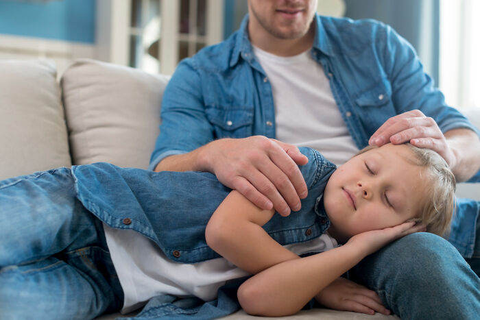 Man babysitter comforting a sleeping child on a couch, illustrating babysitters sharing horror experiences.
