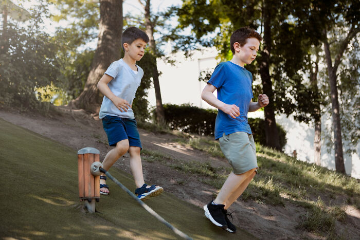 Two boys playing outdoors on a grassy hill, illustrating babysitters' unexpected horror experiences during bedtime.