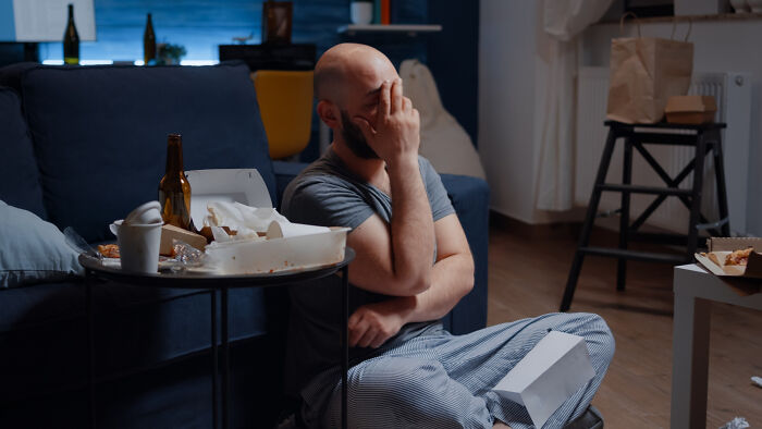 A stressed babysitter sitting on the floor surrounded by food and drink, reflecting on a horror experience during bedtime.