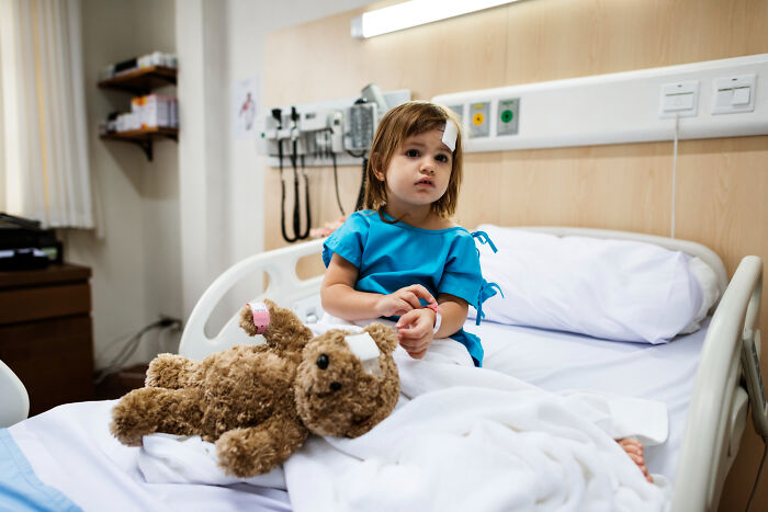 Child with bandages in hospital bed holding a teddy bear, depicting a babysitter horror experience story scenario.