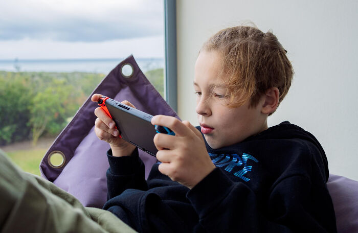 Child playing video game indoors, illustrating babysitting and bedtime stories turning into horror experiences.