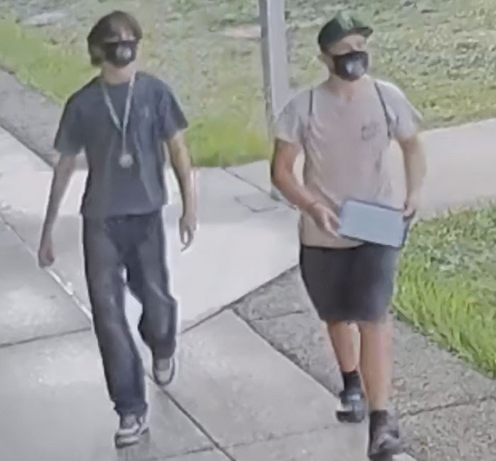 Two young boys wearing masks walking on a sidewalk near grass, related to mothers turning in their children to police.