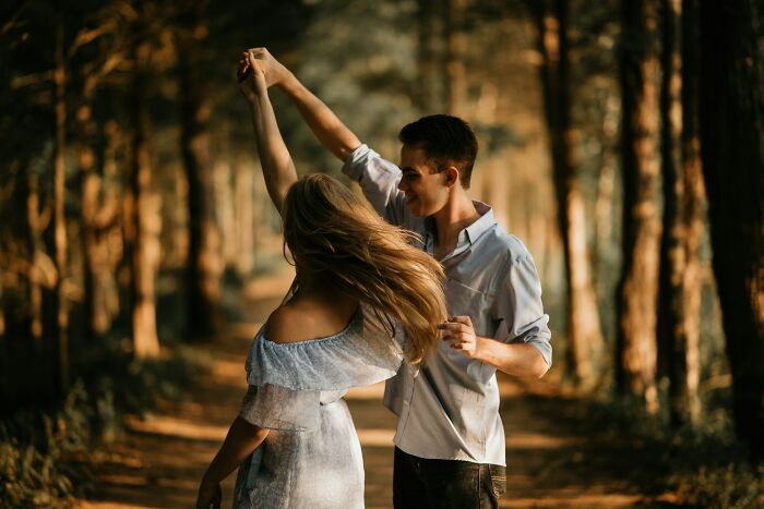 Couple dancing happily in a forest path, illustrating tips for men in happy marriages and maintaining great relationships.