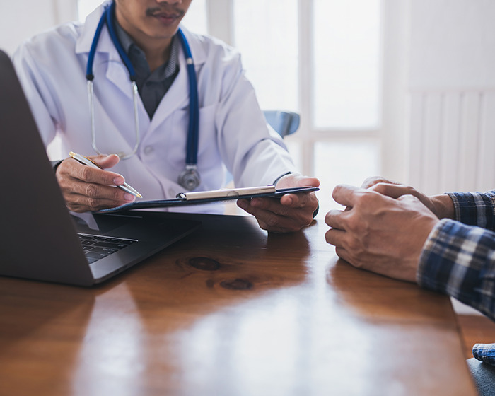 Doctor with stethoscope discussing scrotox cosmetic trend with male patient in a clinical consultation setting.