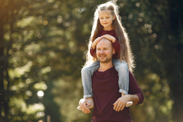 Man carrying young girl on shoulders outdoors, illustrating family dynamics and challenges with entitled disabled bro situation.
