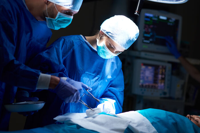 Surgeons in blue scrubs and masks performing an operation, representing professions not seen as relationship material.