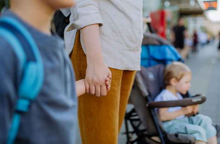 Child holding an adult's hand near a stroller, representing moments when school gossip turned out to be facts exposed.
