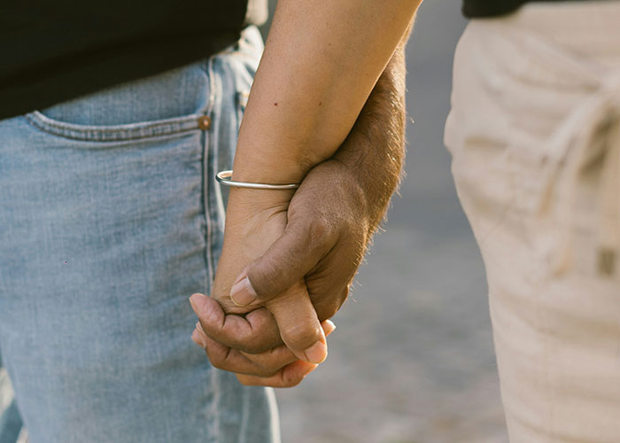 Two people holding hands closely, symbolizing connection and trust amid dark secrets in family relationships.