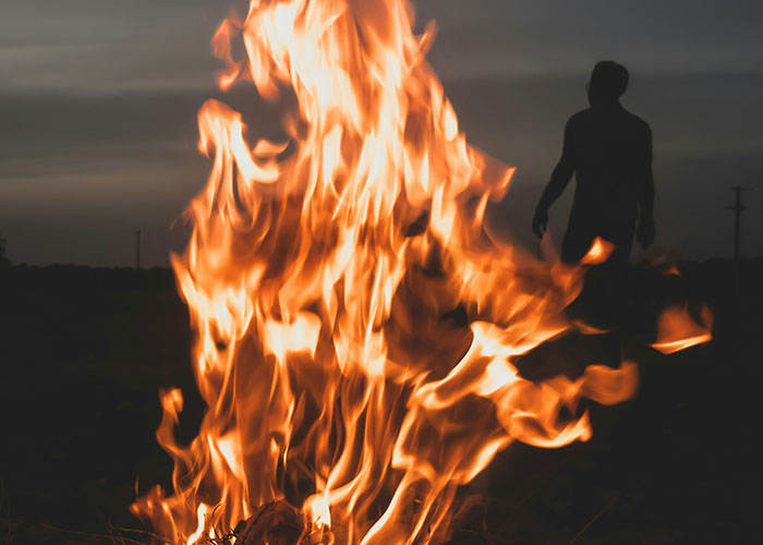 Silhouette of a person near large flames at dusk, illustrating dark secrets people found out about family members.