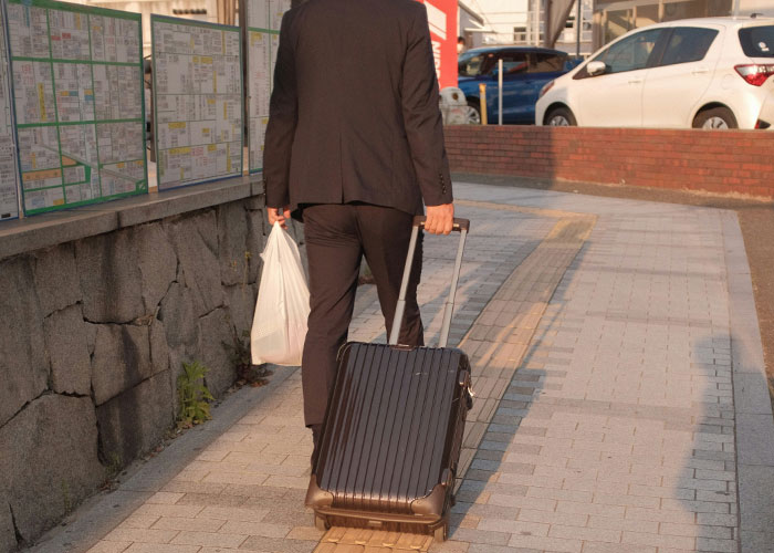 Man in a suit walking with suitcase and plastic bag on sidewalk, reflecting dark secrets that changed family views.