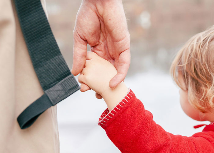 Adult and child holding hands closely, illustrating family bonds and the impact of dark secrets on family relationships.