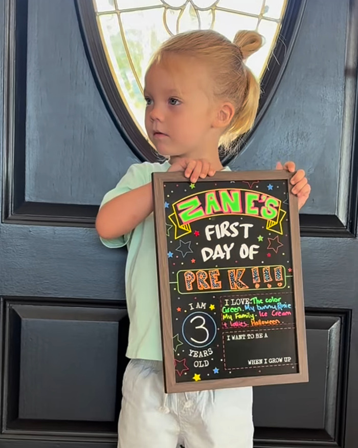 3-year-old child holding a colorful first day of Pre-K sign, highlighting feminine appearance and trolls backlash.