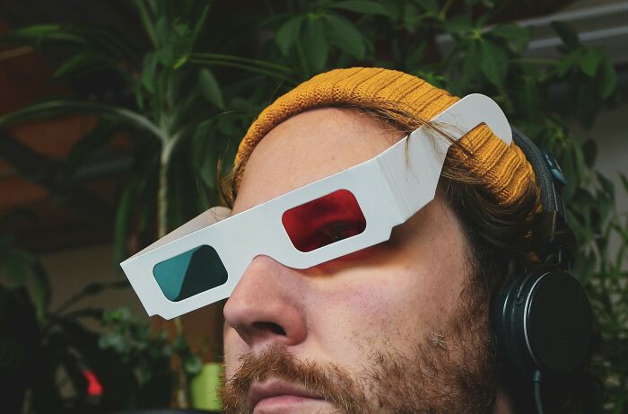 Man wearing 3D glasses and a yellow beanie, headphones on, representing the next big thing that totally flopped concept.