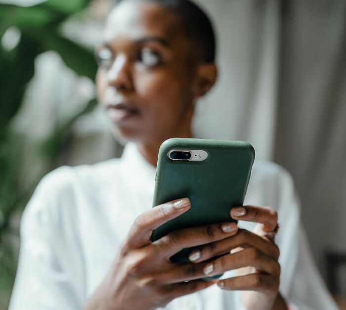 Woman holding smartphone, looking away thoughtfully, illustrating therapy dog banned from family BBQ reality check. Woman holding smartphone, looking away thoughtfully, illustrating therapy dog banned from family BBQ reality check.