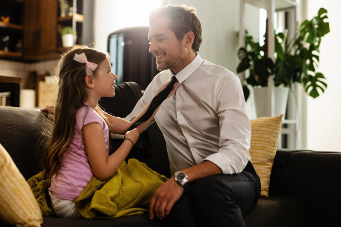 Man in white shirt and little girl playing with his tie on a couch, highlighting family dynamics and aunt’s refusal to babysit. Man in white shirt and little girl playing with his tie on a couch, highlighting family dynamics and aunt’s refusal to babysit.