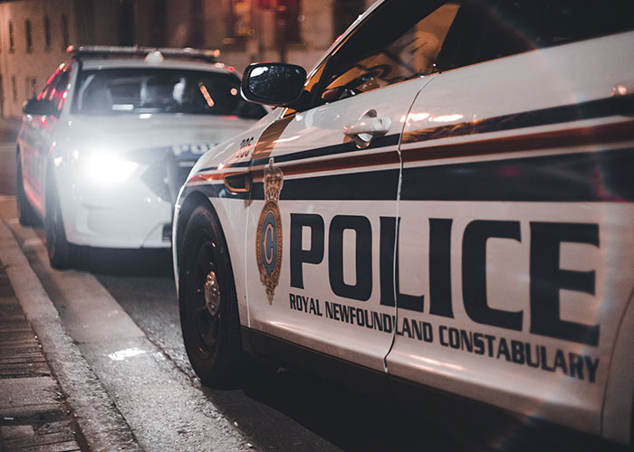 Police car parked at night on a city street related to sister threatening to call the cops after woman brings her kids home.