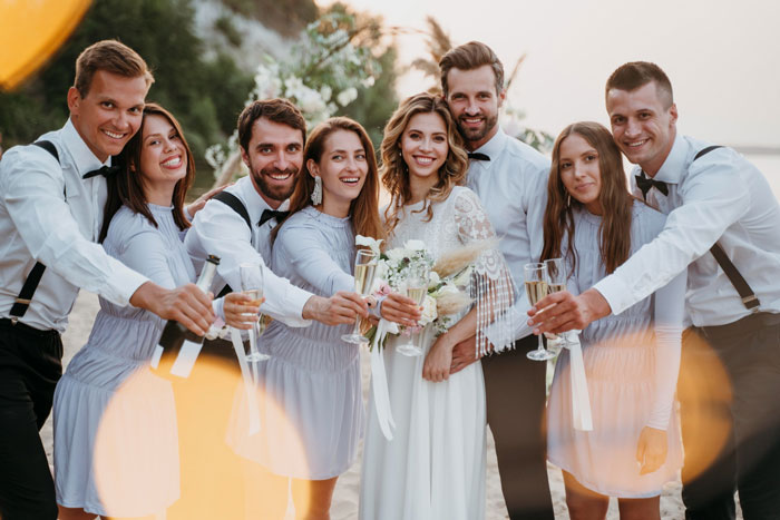 Bride and groom surrounded by wedding party raising champagne glasses, highlighting family favoritism and twin tension at ceremony.