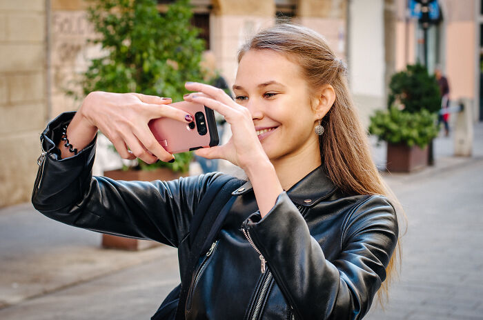 Young woman in a leather jacket taking a selfie outdoors, representing tests women use to spot red flags on dates