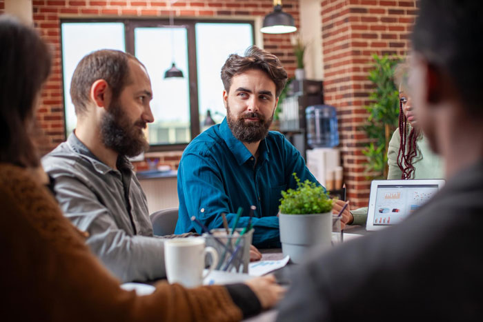 A group of coworkers in a modern office discussing workplace harassment concerns during a team meeting. A group of coworkers in a modern office discussing workplace harassment concerns during a team meeting.